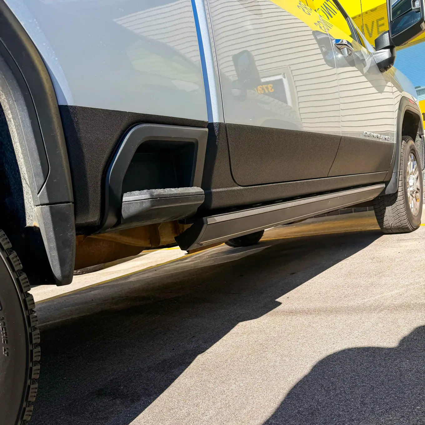 GMC pickup with freshly sprayed black rocker panel coating, parked outside the Pro-Line Coatings shop