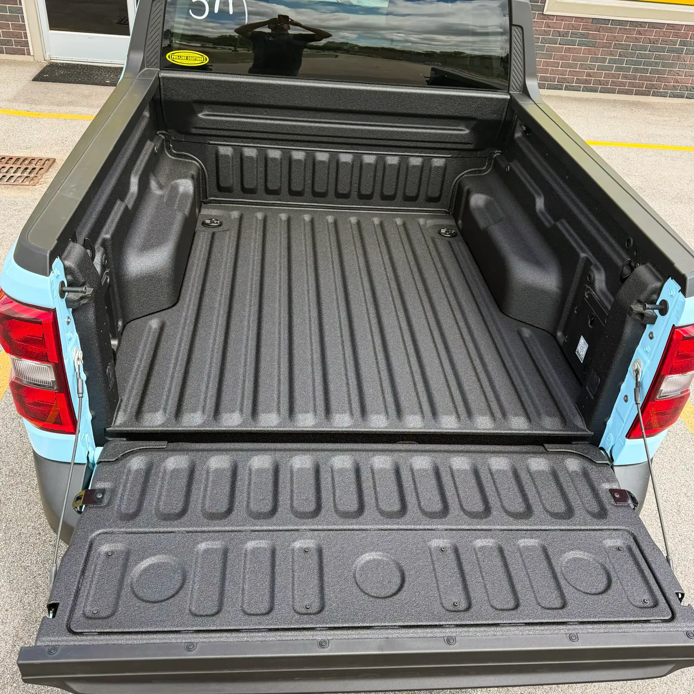 Light blue pickup with black spray-on bedliner covering the bed and tailgate