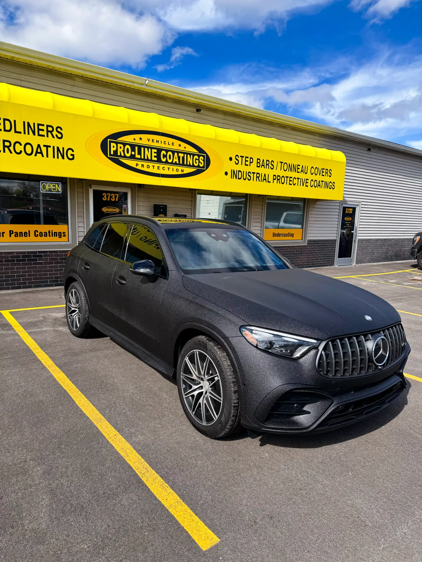 Matte black Mercedes-AMG SUV parked in front of the Pro-Line Coatings storefront