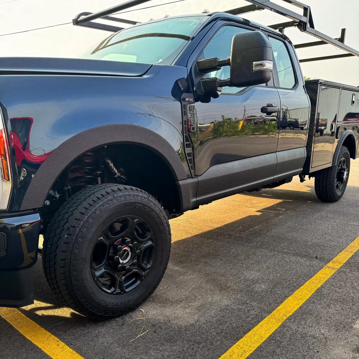 Black Ford Super Duty with coated utility body and ladder rack